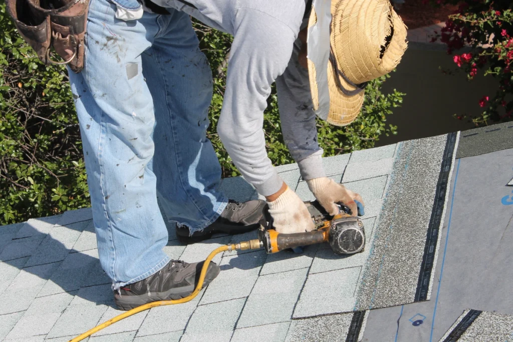 man using nail gun on roof