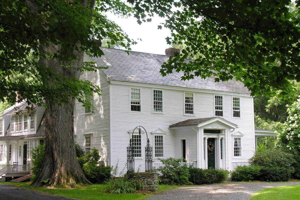 Historic white two-story house with an aged-looking shingle roof.